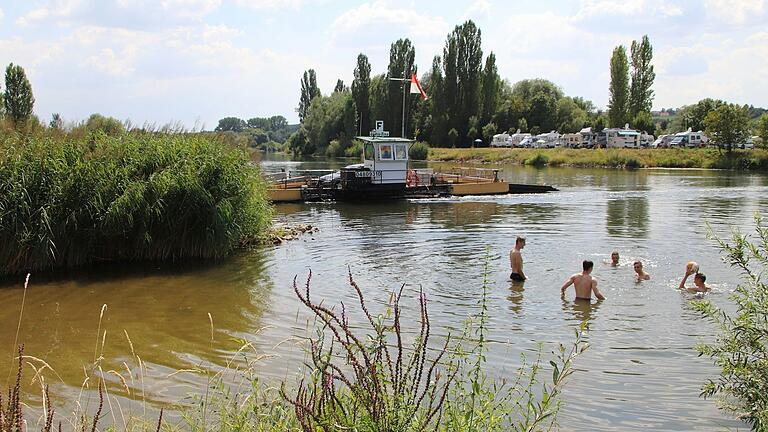 Jugendliche spielen Wasserball im Main, während im Hintergrund die Fähre von Mainstockheim nach Albertshofen übersetzt.