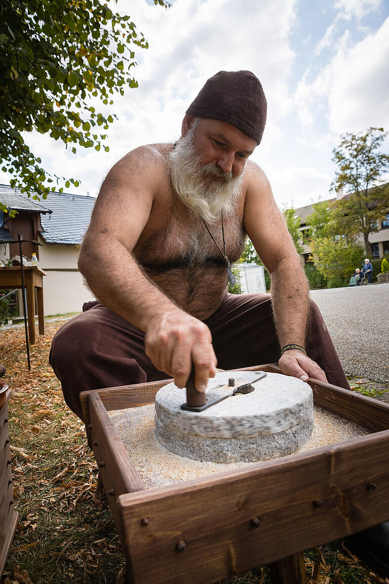 Ein Bauer des „Kleinwenkheimer Bauernhaufens“ mahlt auf ganz traditionelle Weise das Korn zu Mehl.