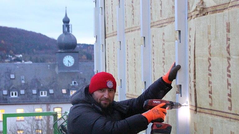 Von einer Hebebühne aus montiert ein Arbeiter die Stahlkonstruktion für die Fassadenverschalung. Foto: Benedikt Borst       -  Von einer Hebebühne aus montiert ein Arbeiter die Stahlkonstruktion für die Fassadenverschalung. Foto: Benedikt Borst