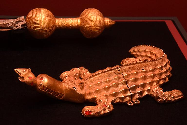Ein goldenes Krokodil frisst einen ebensolchen Fisch.