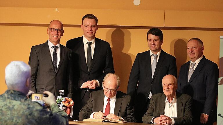 Regierungspräsident Dr. Eugen Ehmann trägt sich ins goldene Buch des Marktes Wildflecken ein. Die versammelte Politprominenz tut es ihm anschließend nach.       -  Regierungspräsident Dr. Eugen Ehmann trägt sich ins goldene Buch des Marktes Wildflecken ein. Die versammelte Politprominenz tut es ihm anschließend nach.