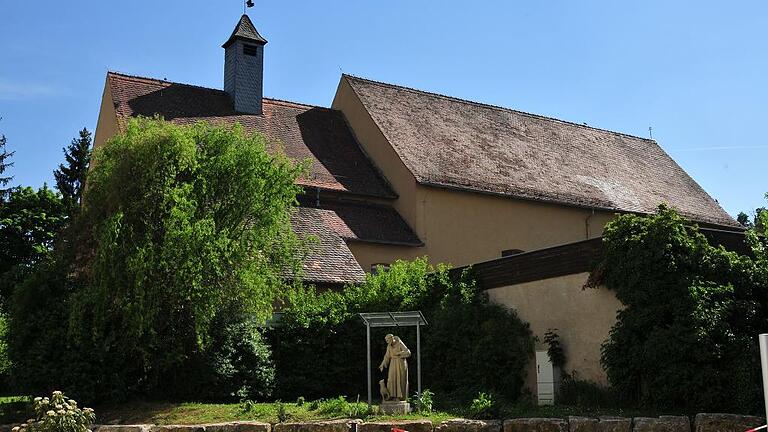Zum Jubiläum die Klosterkirche entdecken       -  Ganz bescheiden versteckt sie sich zwischen dem Altenheim Haus Franziskus und der verkehrsreichen B 13 &ndash; die Klosterkirche der Kapuziner in Ochsenfurt. Dabei birgt sie Kunstschätze, die zu sehen sich lohnt. Der Arbeitskreis Geschichte der Stadt Ochsenfurt nimmt das 350-jährige Bestehen des Gotteshauses zum Anlass für eine ausführliche Vorstellung. Das Programm reicht von Musik über Vorträge bis hin zum Festgottesdienst. Herbert Neeser, Ruhestandspfarrer und gebürtiger Gaukönigshöfer, kennt sich aus in der Klosterkirche, von der viele nicht mehr wissen, als dass sie eine bemerkenswerte Weihnachtskrippe beherbergte. Schon 2016 hatte sich Neeser anlässlich des Tags des offenen Denkmals mit dem Bauwerk beschäftigt. Wenn er die fast schäbig wirkende Seitentür der Kirche mit einem altertümlichen Schlüsselungetüm öffnet, tut sich dahinter ein Gotteshaus mit erstaunlich prachtvollem Hochaltar auf. Das Bild darin hat der Würzburger Hofmaler Oswald Onghers gemalt, erklärt Pfarrer Neeser. Und seitlich davon in der Antoniuskapelle durfte sich sein Zeitgenosse und schärfster Konkurrent verewigen &ndash; Johann Baptist de Ruel, Niederländer wie Onghers und ein mindestens ebenso guter Maler. Vom andauernden Wettstreit der beiden erzählt eine alte Geschichte: Onghers soll, als er das Gemälde de Ruels für die Klosterkirche erblickte, dessen künstlerische Überlegenheit neidlos anerkannt haben. Wer die sechs Passionsbilder im Kirchenschiff geschaffen hat, ist nur zum Teil bekannt. An diesen Bildern ist für Herbert Neeser ohnehin etwas ganz Anderes wichtig: die Wappen nebst Namen der Ochsenfurter Bürger, die diese Bilder gestiftet hatten. Sie alle stammen noch aus der Anfangszeit der Kirche, die am 16. Oktober 1667 geweiht wurde. Die Ansiedelung der Kapuziner in Ochsenfurt war Folge der fürchterlichen Pestjahre während des 30-jährigen Krieges in den 1660er Jahren, erklärt Toni Gernert vom Arbeitskreis Geschichte. Damals hatten die frommen Brüder der gebeutelten Bevölkerung in und um Ochsenfurt beigestanden, als andere Seelsorger längst geflohen oder selbst der Seuche zum Opfer gefallen waren. Als die Kapuziner dann in der Stadt ein Kloster errichten wollten, stand das Domkapitel ihrem Anliegen wohlwollend gegenüber. Das nur mit Spenden errichtete Bauwerk kann nicht verhehlen, dass es von Kapuzinern geplant wurde: ein einfaches Langhaus, ein durch eine Altarwand geteilter Chor, hinter dem sich das Oratorium für die Brüder verbirgt, und ein kleines Glockentürmchen. Der Zugang zu einer Krypta mit 48 Gräbern ist heute unter einem grünen Teppich verborgen. Die Kanzel, erklärt Pfarrer Neeser, sei erst 1670 dazu gekommen, und noch viel später eine Orgel. Die Säkularisation läutete auch in Ochsenfurt das Ende des Klosters ein. 1825 forderte der bayerische König die frommen Brüder auf, sich anderswo eine neue Bleibe zu suchen. Vier Jahre später verließ der letzte Kapuziner Ochsenfurt. Die Stadt kaufte das Kloster und richtete dort ein Pfründnerspital ein. Später wurde der Klosterbau abgerissen und das Altenheim Haus Franziskus errichtet, das mittlerweile auch schon wieder einem Neubau gewichen ist. Die Klosterkirche hat all das überdauert. Zwar wurde sie ihres Kreuzgangs beraubt, und das Oratorium diente bis vor Kurzem als Lagerraum. Doch Pfarrer Neeser ist überzeugt davon, dass der Innenraum schon durch frisch getünchte Wände stark gewinnen würde. Aber auch ohne eine solche Kur ist die Klosterkirche sehenswert, finden Herbert Neeser und Toni Gernert. Vor allem, wenn, wie geplant, das Oratorium wieder zu sehen sein wird. Anlässlich des Jubiläums wird es übrigens 1000 Flaschen &bdquo;Kirchweihbier&ldquo; geben. Die Kauzen-Bräu, hervorgegangen aus der Klosterbrauerei, wird ihr Bier in Flaschen mit eigens gestaltetem Etikett abfüllen.