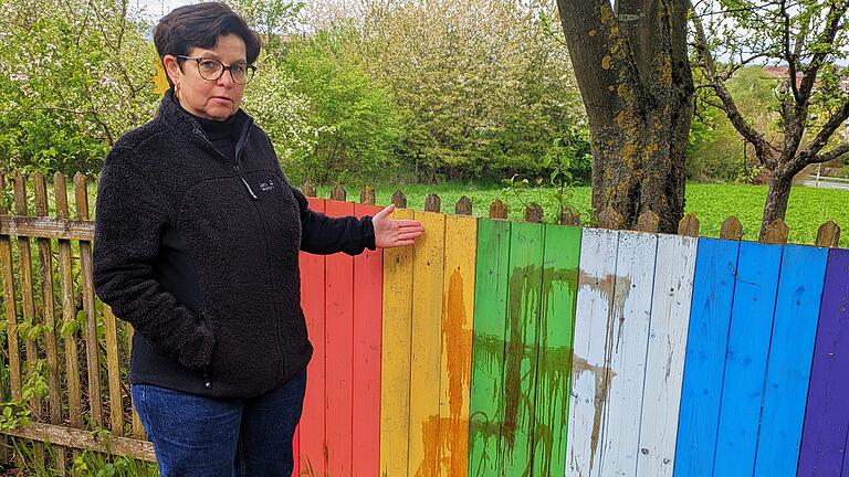 Hakenkreuz-Schmiererei Nüdlingen       -  Vereinsvorsitzende Brigitte May zeigt das große Hakenkreuz am Regenbogenzaun des Gartens.