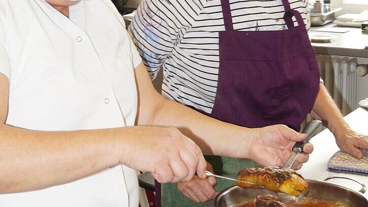 Lehrerin Ruth Halbritter hebt die Kohlrouladen, die Petra Wieland gekocht hat, aus der Pfanne und schneidet sie auf.