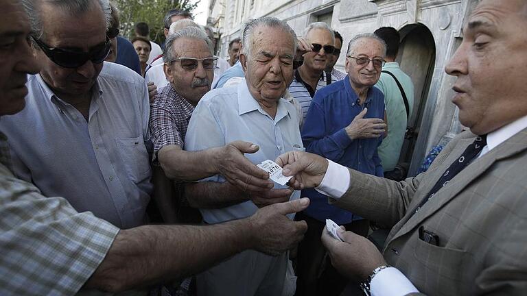 Greek banks reopened       -  Anstehen für Geld: In Athen teilt ein Bankmitarbeiter Platznummern für die Warteschlange vor dem Geldhaus aus.