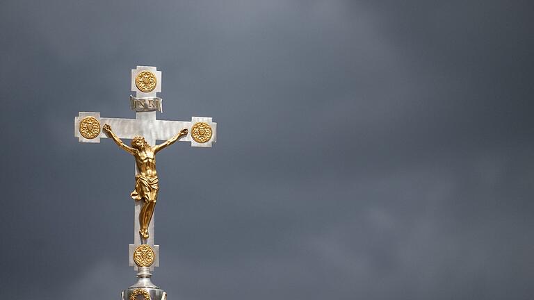 Christliches Kreuz - Ein katholisches Kruzifix ist vor dunklen Wolken zu sehen. Symbolbild Christliches Kreuz - Ein katholisches Kruzifix ist vor dunklen Wolken zu sehen. Symbolbild