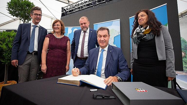 Beim Jubiläums-Festakt trägt sich Ministerpräsident Markus Söder ins Goldenen Buch des Landkreises Würzburg ein, flankiert vom Würzburger Oberbürgermeister Christian Schuchardt, Bezirksrätin Rosa Behon, Landrat Thomas Eberth und der stellvertretenden Landrätin Christine Haupt-Kreutzer.