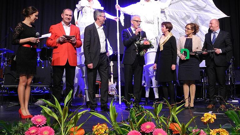 Ganz viel Stolz auf die neue Stadthalle       -  (HuHe)   Es war eine wundervolle Show, mit der die Stadt Bad Neustadt die Einweihung der neuen Stadthalle feierte. Nach einer phantastischen Lasershow, die noch einmal die Geschichte vom Abriss der alten Stadthalle und dem Neubau wiedergab, trat sichtlich gut gelaunt Bürgermeister Bruno Altrichter (Vierter von rechts) auf die Bühne, um die Gäste im vollen Saal zu begrüßen. Bevor die Dekane Andreas Krefft und Matthias Büttner dem Neubau ihren Segen erteilten, gab es viele lobende Worte von Staatsekretär Gerhard Eck, Staatssekretärin Dorothee Bär und vom stellvertretenden Landrat Josef Demar. Den symbolischen Schlüssel überreichte Architekt Michael Bracke (Driiter von links) an Bürgermeister Bruno Altrichter, der ihn aber gleich an die Stadthallenmanagerin Petra Lettang und den Chef der Tourismus-GmbH Michael Feiler (auf der rechten Seite) weiterreichte. Einen Blumenstrauß erhielt Stadtbaumeisterin Barbara Stüdlein (Dritte von links). Mit ihnen freuten sich die Moderatoren des Abends Verena Seufert und Fredi Breunig.