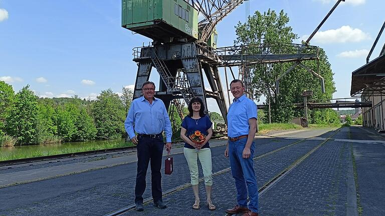 Bürgermeister Peter Juks (rechts), die neue Hafenmeisterin Beate Haager und Vorgänger Kilian Popp bei der Amtsübergabe vor dem alten Kran auf dem BayWa-Gelände in Ochsenfurt.