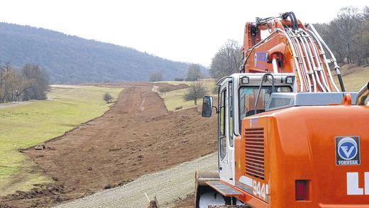 Bau der 67 Kilometer langen Gasleitung hat begonnen       -  (dübi)    Riesige Erdbewegungen und eine neue Waldschneise am Talhang zwischen Morlesau und der Rossmühle künden vom Baubeginn an der Erdgasfernleitung zwischen dem hessischen Sannerz und Rimpar. Von der Mitte des rund 67 Kilometer langen Projektes arbeiten sich Raupen und Bagger gleichzeitig nach Norden und nach Süden vor. Dabei stellt der tiefe Einschnitt des Saaletals gleich eine besondere Herausforderung für die Arbeiter und Ingenieure dar. Seit einer Woche wird auf Wiesen und Äckern Mutterboden zur Seite geschoben, im Wald Bäume gefällt und Wurzelwerk entfernt sowie erster Rohrgrabenaushub ausgebaggert. Von der geschaffenen Fahrtrasse aus werden in Kürze schwere Raupen rund 18 Meter lange und 7,5 Tonnen schwere Rohrabschnitte zum Verschweißen in den Graben hieven. Täglich sollen rund 500 Meter Rohre verlegt werden. Die Bauleitung ist im ehemaligen Baywa-Haustechnik-Fachmarkt in Hammelburg untergebracht. Voraussichtlich bis November schwärmen von hier 40 Fachleute aus, um das Projekt voranzubringen. Ingenieure, Kaufleute, Transportexperten, Technischer Überwachungsverein und Biologen sind für jene Hürden zuständig, die sich entlang der Strecke auftun.