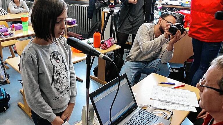 Schüler der Leonhard-Frank-Grundschule sprechen in ihrem Klassenzimmer Haltestellen-Namen zur Aufnahme in ein Mikrofon. Schüler der Leonhard-Frank-Grundschule sprechen in ihrem Klassenzimmer Haltestellen-Namen zur Aufnahme in ein Mikrofon.
