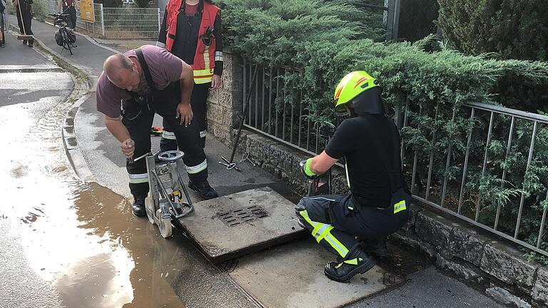 Die Feuerwehr öffnet Kontrollschächte auf dem Gehweg, um zu überprüfen, ob diese auch schon vollgelaufen sind.