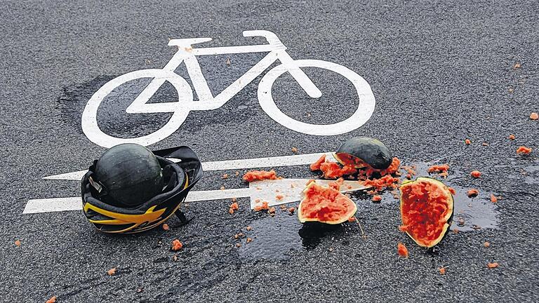 Eindrucksvoller Test: Geschützt durch einen Fahrradhelm bleibt die Melone, die zu Boden fällt, ganz. &bdquo;Oben ohne&ldquo; zerfetzt es die Frucht.