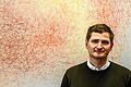 Professor Jörg Vogel in seinem Büro im Institut für Molekulare Infektionsbiologie. Hinter seinem Schreibtisch hat er keine stark vergrößerte Aufnahme von Zellen unter dem Mikroskop hängen, sondern den Siebdruck einer Textildesignerin.