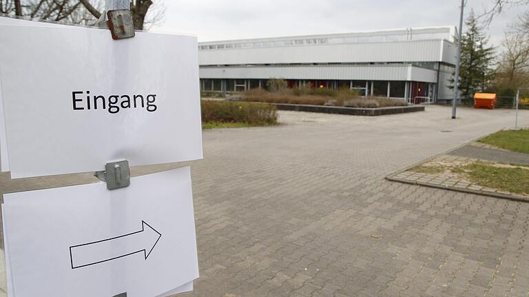 Ein Schild weist in Richtung Eingang der Teststrecke für Patienten mit Verdacht auf das Coronavirus in der Turnhalle des Alexander-von-Humboldt-Gymnasiums in Schweinfurt hin.