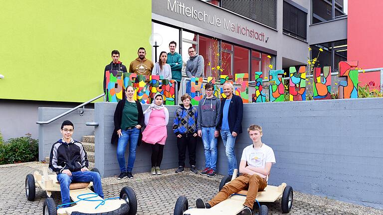 Die Schüler der Klasse 8p der ULMS stellten ihre neuesten Projektergebnisse vor: Seifenkisten und das Schulmotto, sprich: den in Steine gehauenen Schriftzug „Gegen Rassismus“. Mit im Bild: Techniklehrer Manuel Wengel (oben rechts), Sozialpädagoge Martin Beck (oben, Zweiter von links) sowie die beiden Schulleiter, Konrektorin Melanie Dotzer (unten links) und Rektor Achim Libischer (unten rechts). Die „Piloten“ auf den Gefährten sind Mohammad Almahamid (links) und Odin Schwarzfischer. Die Schüler der Klasse 8p der ULMS stellten ihre neuesten Projektergebnisse vor: Seifenkisten und das Schulmotto, sprich: den in Steine gehauenen Schriftzug „Gegen Rassismus“. Mit im Bild: Techniklehrer Manuel Wengel (oben rechts), Sozialpädagoge Martin Beck (oben, Zweiter von links) sowie die beiden Schulleiter, Konrektorin Melanie Dotzer (unten links) und Rektor Achim Libischer (unten rechts). Die „Piloten“ auf den Gefährten sind Mohammad Almahamid (links) und Odin Schwarzfischer.