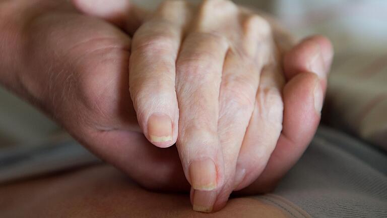 Ein Altenpfleger hält in einem Pflegeheim die Hand einer Frau. Das Bundesverfassungsgericht hat am Mittwoch das Verbot der geschäftsmäßigen Sterbehilfe in Deutschland für verfassungswidrig erklärt.