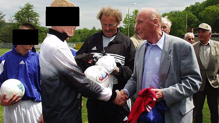 BG Eckel JVA Balken       -  Die JVA Ebrach hatte bereits einmal Kontakt mit der DFB-Stiftung Sepp Herberger: In ihrem Namen überreichte im Mai 2004 Fußball-Legende Horst Eckel, Mitglied der Weltmeistermannschaft von 1954 (rechts vorne), auf dem Sportplatz des SC Ebrach Gefangenen der Justizvollzugsanstalt Sportbekleidung und Sportausrüstung. Archiv-