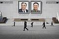 Nordkorea       -  Passanten auf dem Kim-Il-Sung-Platz in Pjöngjang (Nordkorea). Auf den Gemälden sind die verstorbenen nordkoreanischen Diktatoren Kim Il Sung (links) und Kim Jong Il zusehen.