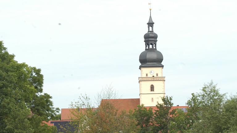 Der Kirchturm von Irmelshausen vom Gelände der Firma Caldatrac gesehen. Rechts vom Turm, in gut 120 Meter&nbsp; Abstand soll der 5 G-Mast errichtet werden.