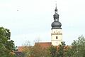 Der Kirchturm von Irmelshausen vom Gelände der Firma Caldatrac gesehen. Rechts vom Turm, in gut 120 Meter&nbsp; Abstand soll der 5 G-Mast errichtet werden.