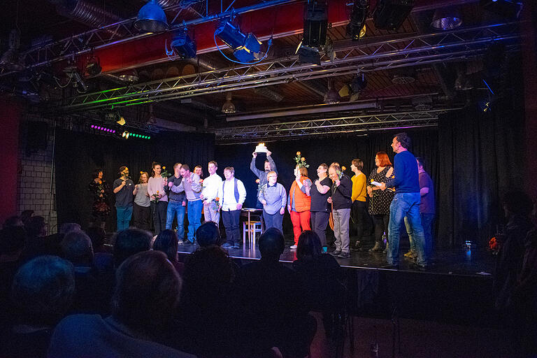 Das Ensemble singt beim Kerzenschein einer Torte dem Theater gemeinsam ein „Ständchen“