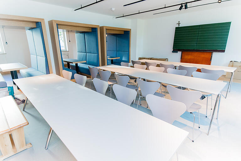 Im Seminarraum im Erdgeschoss erinnert die Tafel aus den 50er Jahren daran, dass hier einst ein Klassenzimmer war. Die Sitzecken öffnen sich zum Gang.&nbsp;