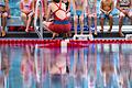 Kinder sitzen währen eines Schwimmkurses auf einer Bank im Hallenbad (Symbolbild). Wegen der abgesenkten Temperaturen frieren manche Kinder nun im Wasser.