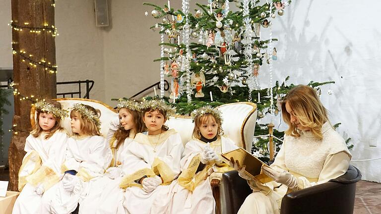 Der Gerolzhöfer Weihnachtsengel Aliya Reichert (rechts), las die Weihnachtsgeschichte 'Pelle zieht aus' von Astrid Lindgren, aus einem goldenen Buch vor. Die Engelsschaar (links) stand ihr dabei zur Seite. Der Gerolzhöfer Weihnachtsengel Aliya Reichert (rechts), las die Weihnachtsgeschichte 'Pelle zieht aus' von Astrid Lindgren, aus einem goldenen Buch vor. Die Engelsschaar (links) stand ihr dabei zur Seite.