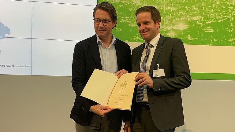 Baureferent Benjamin Schneider nimmt aus den Händen von Bundesminister Andreas Scheuer den Green-City-Förderbescheid entgegen.