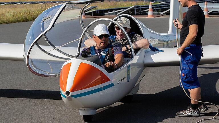 Im Lehrflugzeug sitzt Lehrer Arnulf Koch hinter seinem Schüler Lothar Pfeiler. Markus Neubert befestigt die Seilwinde.