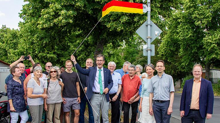 Oberbürgermeister Christian Schuchardt enthüllt das Straßenschild „Rosa-Buchbinder-Straße“ mit Anwohnerinnen und Anwohnern sowie Stadtratsmitgliedern. Außerdem dabei waren der Leiter des Stadtarchivs Axel Metz und Dirk Terwey vom Mainfranken Theater.