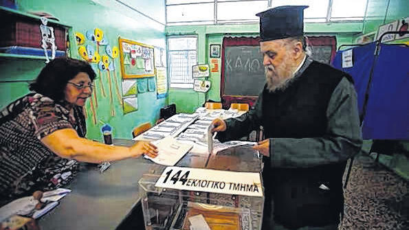 In einer Schule: Ein orthodoxer Priester geht in Athen zu Wahl.