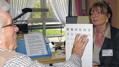 Buchstaben erkennen: Orthoptistin Sabine Kampmann prüft Erna Haupts Sehfähigkeit an der Lesetafel.