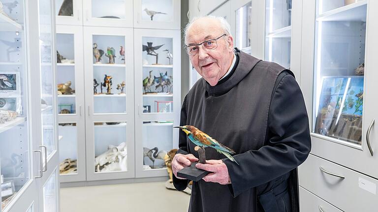 Pater Franziskus Büll steht in der Biologischen Sammlung der Abtei Münsterschwarzach mit einem ausgestopften Bienenfresser in der Hand.