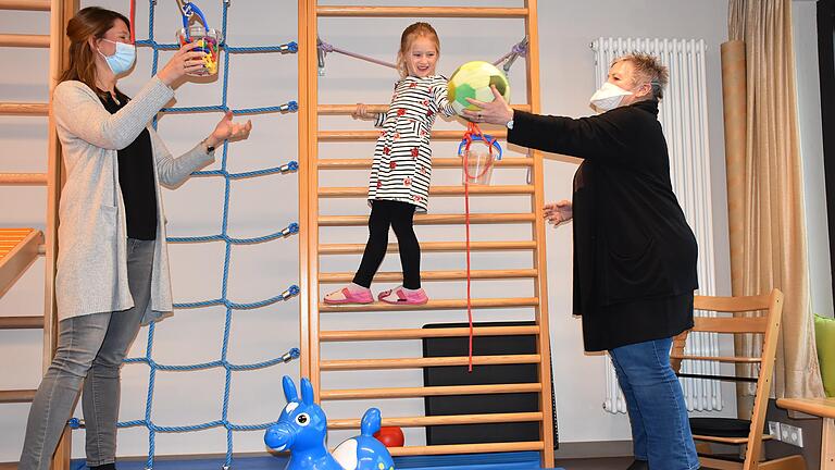 Immer gut festhalten und den Ball weitergeben. Mathilda (5) übt, wie man Klettern und Ballspielen gemeinsam schafft. Ihr assistieren dabei Kristina Bub (links), Koordinatorin der Außenstelle Schweinfurt&nbsp; und&nbsp; Margit Jäcklein, die Leiterin der vier Caritas-Frühförderstellen der Region in Gerolzhofen, Schweinfurt, Haßfurt und Ebern.