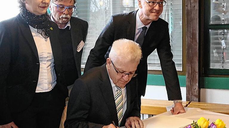 Kretschmann schreibt ins Goldene Buch der Stadt Wertheim - (micz) Auch wenn die Gesprächsrunde mit Ministerpräsident Winfried Kretschmann und rund 50 ehrenamtlich engagierten Bürgern aus dem Main-Tauber-Kreis im Kirchenzentrum Wartberg eine Wahlkampf-Veranstaltung der Grünen war, ließ es sich Bürgermeister Stefan Mikulicz (CDU, im Bild rechts) nicht nehmen, den Landesvater um einen Eintrag ins Goldene Buch der Stadt zu bitten. Kretschmann wünschte Wertheim eine „gedeihliche und nachhaltige Entwicklung zum Wohle ihrer gesamten Bürgerschaft“. Mikulicz nutzte die Gelegenheit und warb um Kretschmanns Unterstützung für die mögliche Ansiedlung einer privaten Fachhochschule in seiner Stadt. Der Ministerpräsident reagierte zurückhaltend. Er wolle nichts zusagen, was er nach Rücksprache mit dem Wissenschaftsministerium nicht halten könne, sagte er. Im Gespräch mit den Ehrenamtlichen waren zuvor zahlreiche Klagen über ein Zuviel an Bürokratie laut geworden, das dem Engagement gerade für Flüchtlinge im Wege stehe. Kretschmann sicherte zu, die zuständigen Behörden zu bitten, sich der Probleme anzunehmen. Schnelle Lösungen versprach er indes nicht. Mit im Bild sind die Grünen-Landtagskandidatin Birgit Väth und Kreisrat Eberhard Feucht. Kretschmann schreibt ins Goldene Buch der Stadt Wertheim - (micz) Auch wenn die Gesprächsrunde mit Ministerpräsident Winfried Kretschmann und rund 50 ehrenamtlich engagierten Bürgern aus dem Main-Tauber-Kreis im Kirchenzentrum Wartberg eine Wahlkampf-Veranstaltung der Grünen war, ließ es sich Bürgermeister Stefan Mikulicz (CDU, im Bild rechts) nicht nehmen, den Landesvater um einen Eintrag ins Goldene Buch der Stadt zu bitten. Kretschmann wünschte Wertheim eine „gedeihliche und nachhaltige Entwicklung zum Wohle ihrer gesamten Bürgerschaft“. Mikulicz nutzte die Gelegenheit und warb um Kretschmanns Unterstützung für die mögliche Ansiedlung einer privaten Fachhochschule in seiner Stadt. Der Ministerpräsident reagierte zurückhaltend. Er wolle nichts zusagen, was er nach Rücksprache mit dem Wissenschaftsministerium nicht halten könne, sagte er. Im Gespräch mit den Ehrenamtlichen waren zuvor zahlreiche Klagen über ein Zuviel an Bürokratie laut geworden, das dem Engagement gerade für Flüchtlinge im Wege stehe. Kretschmann sicherte zu, die zuständigen Behörden zu bitten, sich der Probleme anzunehmen. Schnelle Lösungen versprach er indes nicht. Mit im Bild sind die Grünen-Landtagskandidatin Birgit Väth und Kreisrat Eberhard Feucht.