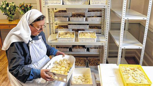Endkontrolle: Schwester Teresa Benedicta sortiert fehlerhafte Exemplare aus, bevor sie Hostien in Papiertüten verpackt.