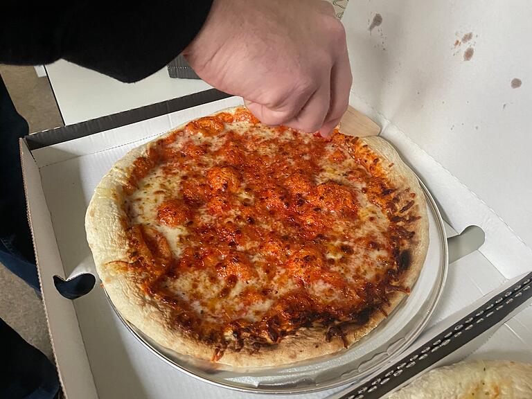 Die Pizza liegt auf einem Aluteller im Karton. Anbei ist ein kleines Holzmesser zum Schneiden. Die Pizza liegt auf einem Aluteller im Karton. Anbei ist ein kleines Holzmesser zum Schneiden.