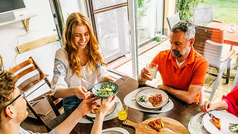 Eine Familie isst gemeinsam       -  Gemeinsames Essen stärkt Bindungen: Regelmäßige Mahlzeiten in Gesellschaft fördern Austausch und emotionale Verbundenheit.