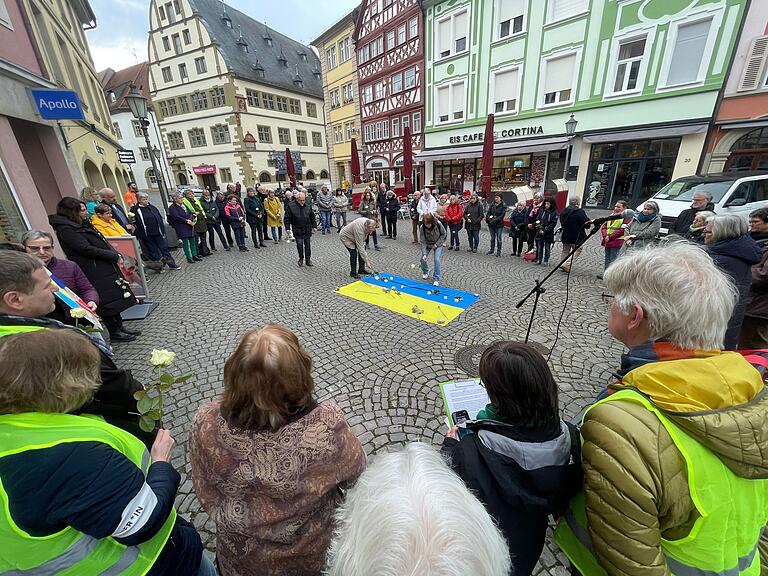 Auf dem Marktplatz legten die Menschen weiße Blumen auf die ukrainische Fahne. Auf dem Marktplatz legten die Menschen weiße Blumen auf die ukrainische Fahne.