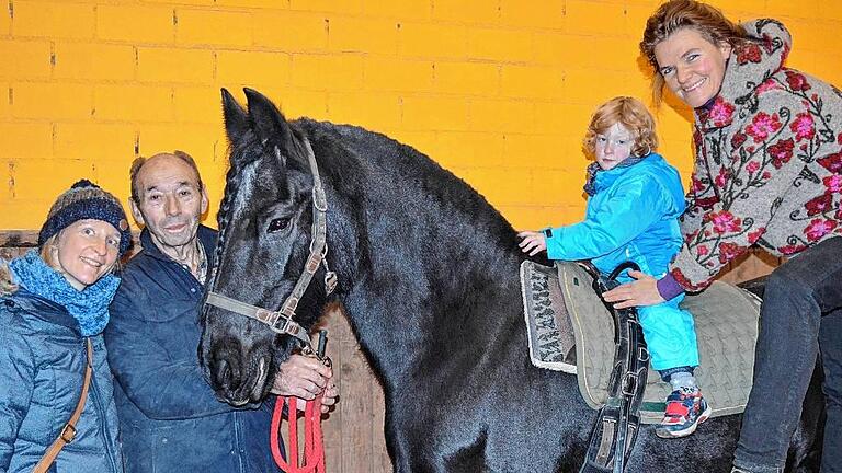 Bequemer Aufstieg: Über eine Rampe setzt Cosima Böttger (rechts) den vierjährigen Luca auf den Rücken des 17-jährigen Friesen Xenia, beobachtet von seiner Mutter Sonja Knoth (links) und Walter Koch. Friesenpferde gelten als gutwillig, sanft und freundlich und sind für die Reittherapie deshalb besonders gut geeignet.