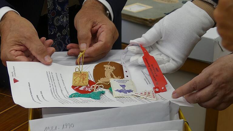 Ob Holz oder Plastik, Anhänger in rund, eckig oder oval, ein Armband oder eine Scheckkarte: Die Weinfestmarken bilden seit jeher die Schlüssel zum Volkacher Weinfest.