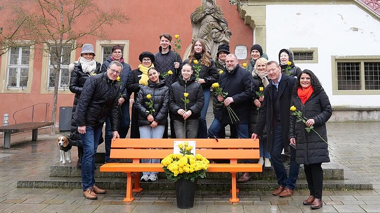 Ein gut sichtbares Signal zum Weltfrauentag 2023: Veitshöchheims Bürgermeister Jürgen Götz (vorne links) übergibt die 'Orangene Bank' an seinen Ochsenfurter Amtskollegen Peter Juks (Zweiter von rechts). Die auffällige „wandernde Bank“ soll im Landkreis Würzburg auf Gewalt an Frauen aufmerksam machen.