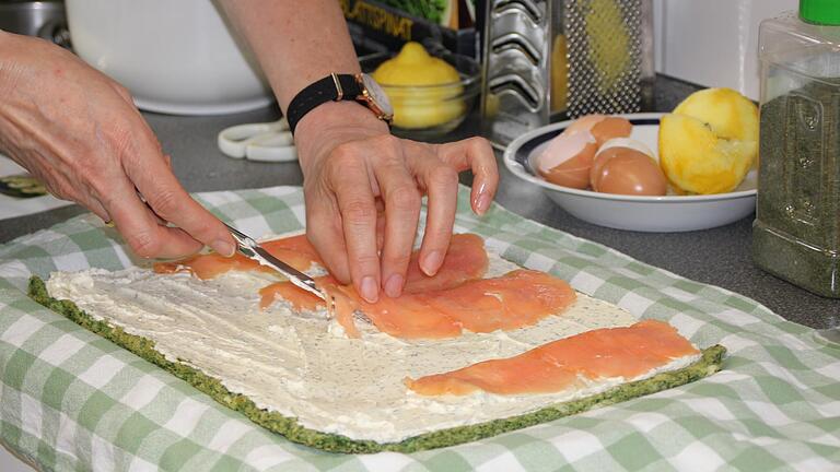 Der gebackene Spinat-Teig wird mit Frischkäse-Masse und Lachs belegt und dann zusammengerollt.