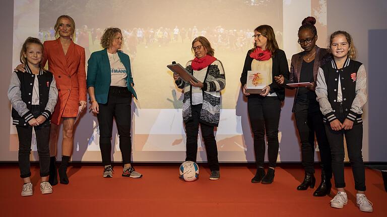 Petra (Mitte) und Hanna Flockerzi (Dritte von rechts) bei der Preisübergabe auf der Bühne.