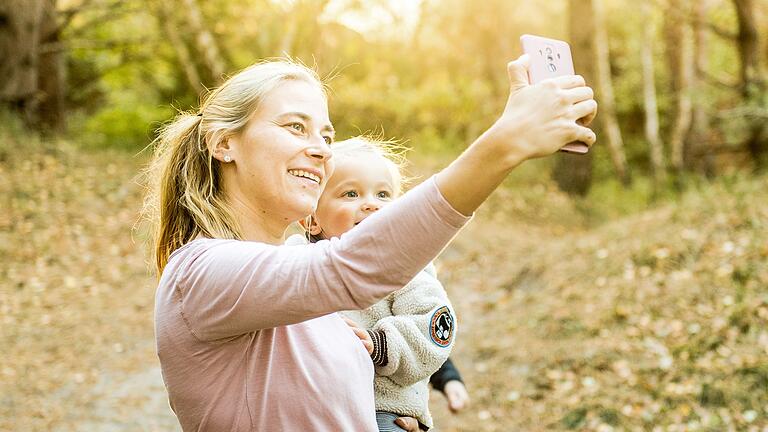 Frau fotografiert Selfie von sich und ihrem Sohn       -  Viele Eltern teilen unbeschwerte Momente mit ihren Kindern im Chat oder posten die Fotos online. Viele dieser Bilder sollten aber besser nicht einfach so geteilt werden.