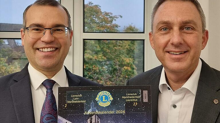 Christian Schall (links), Präsident des Lions-Clubs Marktheidenfeld-Laurentius, und sein Kollege Stephan Kliegl vom Lions-Club Lohr- Marktheidenfeld mit dem Lions-Adventskalender 2024.