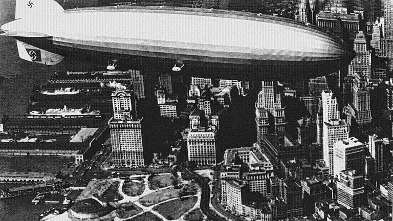 Zeppelin LZ 129 'Hindenburg' über New York - Der Zeppelin LZ 129 „Hindenburg“ über der Südspitze von Manhattan/New York. Der 100 Tonnen schwere, zu seiner Zeit größte Zeppelin der Welt hob vor 80 Jahren zum ersten Mal ab. Zeppelin LZ 129 'Hindenburg' über New York - Der Zeppelin LZ 129 „Hindenburg“ über der Südspitze von Manhattan/New York. Der 100 Tonnen schwere, zu seiner Zeit größte Zeppelin der Welt hob vor 80 Jahren zum ersten Mal ab.