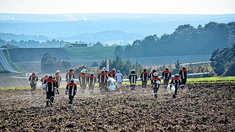 Ein Segelflieger muss auf einem Feld in der Nähe von Urspringen notlanden, weil ihn die Thermik im Stich lässt und ihm jeglicher Aufwind fehlt. Der junge Mann bleibt glücklicherweise unverletzt. Feuerwehrleute helfen bei der Bergung und transportieren das rund 275 Kilogramm schwere Segelflugzeug zur nächsten Straße.